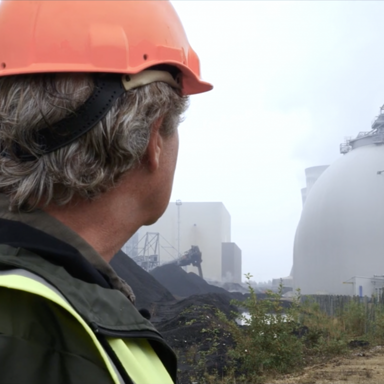 Tony Juniper at Drax Power Station between coal stock and biomass wood pellet storage domes